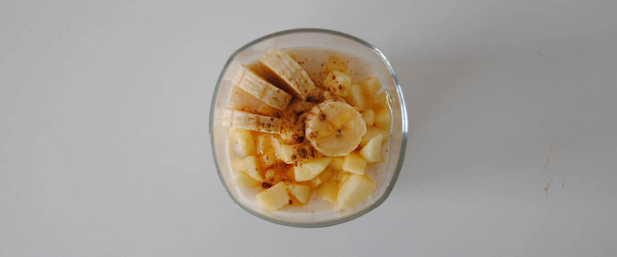 Cups of yogurt, banana, apple and honey